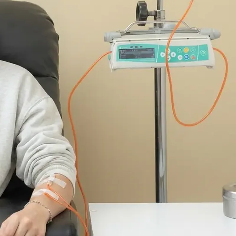 Brazo con vía intravenosa en un sillón de infusión, junto a la bomba programada