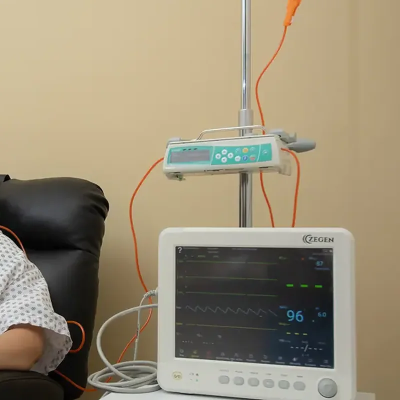 Sala de infusión privada con sillón reclinable, bomba y monitor de signos vitales